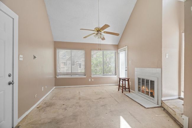 Living area featuring vaulted ceiling, ceiling fan, and a glass covered fireplace | Image 6
