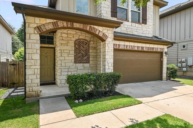 Property entrance with a garage, stone siding, driveway, and board and batten siding | Image 10