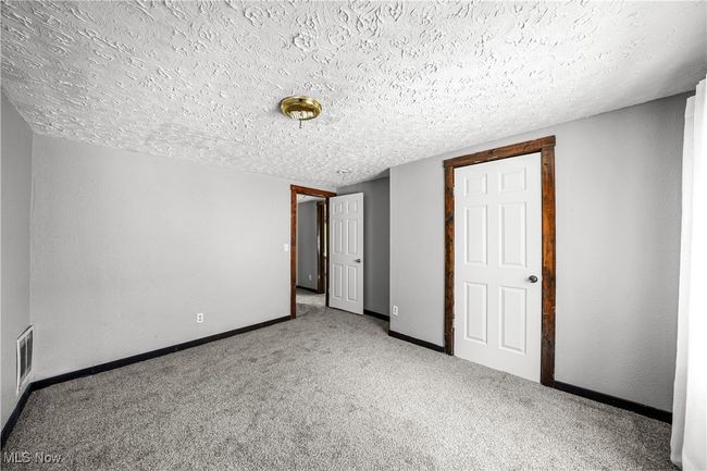 Unfurnished bedroom featuring a textured ceiling and carpet floors | Image 15