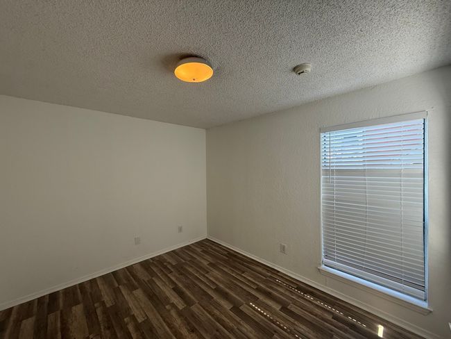 Empty room featuring a textured ceiling, a smoke detector, and dark wood-style floors | Image 12