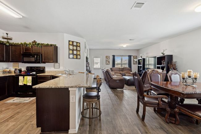 Kitchen featuring black appliances, a sink, a breakfast bar, a peninsula, and dark brown cabinetry | Image 19