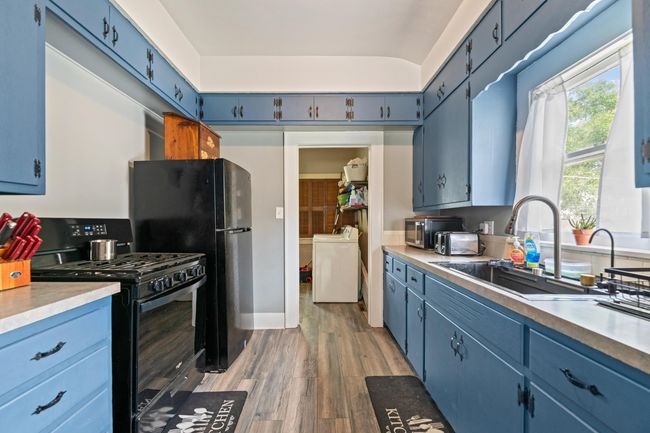 Kitchen featuring black appliances, blue cabinetry, light wood-type flooring, and a sink | Image 29
