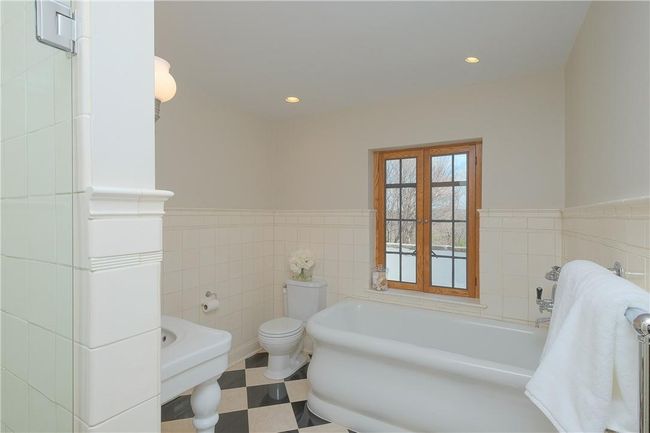 Primary en-suite sparkling white full bath, separate shower with frameless glass enclosure, marble floor, tile surround, rolled edge soaking tub, Cesame sink, recessed lighting | Image 20