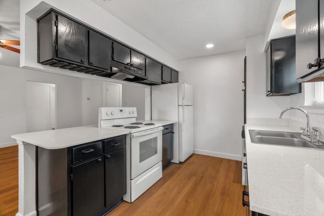 Kitchen with white appliances, a peninsula, light wood finished floors, light countertops, and recessed lighting | Image 17