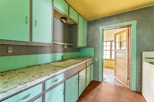 Kitchen with a sink, light wood-type flooring, light countertops, and green cabinetry | Image 9