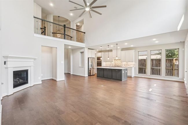 The open-concept living space features soaring ceilings, tall windows, and beautiful wood flooring | Image 9