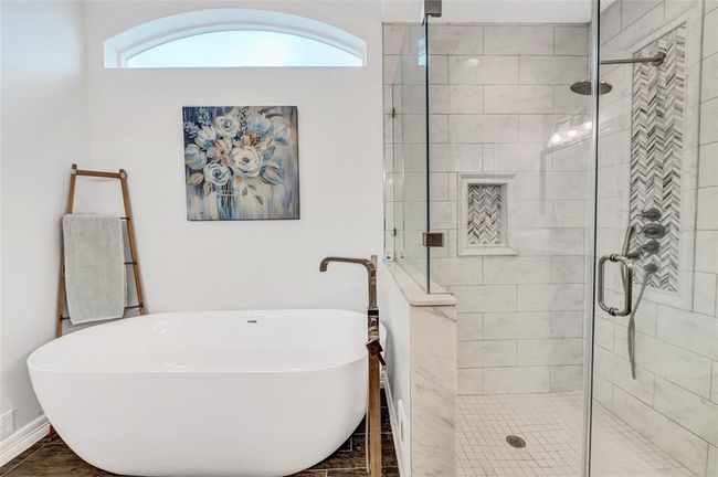 This spa like tub and shower is impeccably designed with a rain shower head, lovely tile and marble herringbone detailing. What a retreat! | Image 21