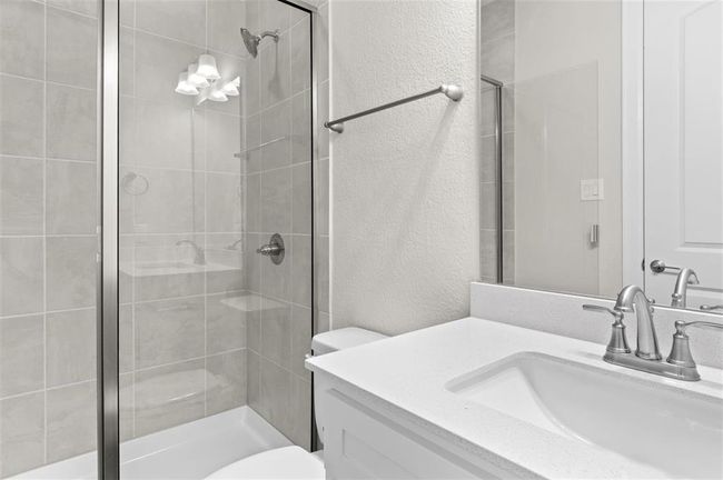 Bathroom with a textured wall, a stall shower, toilet, and vanity | Image 17
