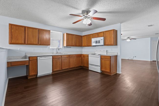 Kitchen featuring dark wood-type flooring, sink, white appliances, and a textured ceiling | Image 6