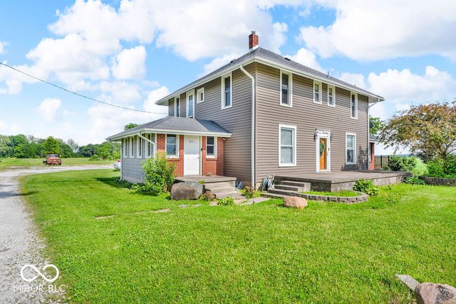 rear view of house featuring a chimney, a lawn, driveway, and brick siding | Image 5