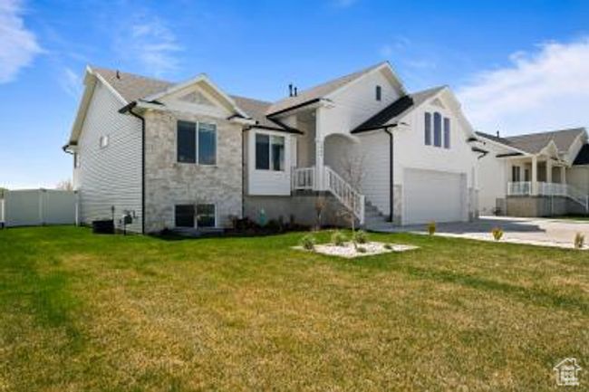View of front facade featuring an attached garage, stone siding, a front yard, and driveway | Image 4