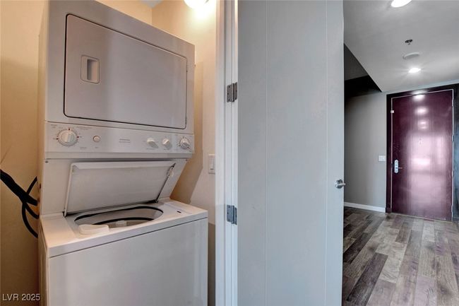 Laundry area featuring baseboards, wood finished floors, stacked washing maching and dryer, and recessed lighting | Image 13