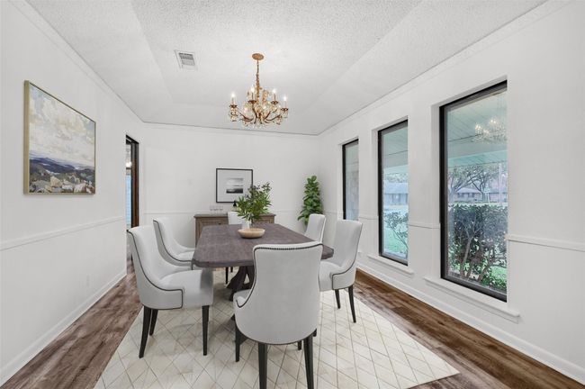 Dining space with a chandelier, wood finished floors, a textured ceiling, and baseboards~ virtually staged | Image 12