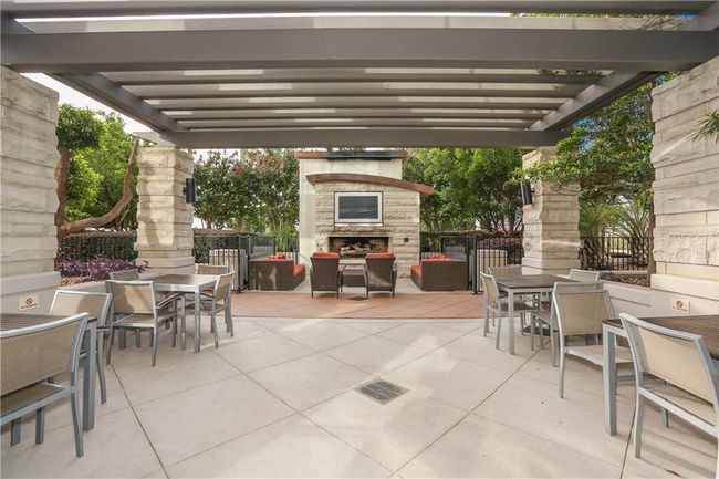 View of patio / terrace featuring a pergola, outdoor dining space, an outdoor stone fireplace, and fence | Image 26