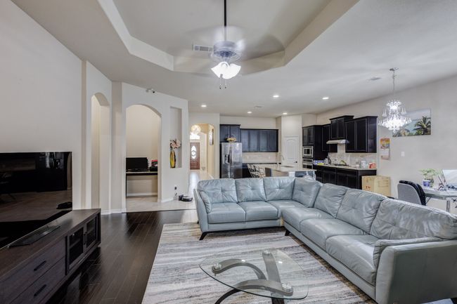 Living area featuring arched walkways, ceiling fan, wood finished floors, a chandelier, and baseboards | Image 15
