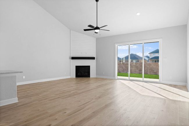 Expansive and inviting, the family room features a fireplace and large windows overlooking the covered back patio. | Image 4