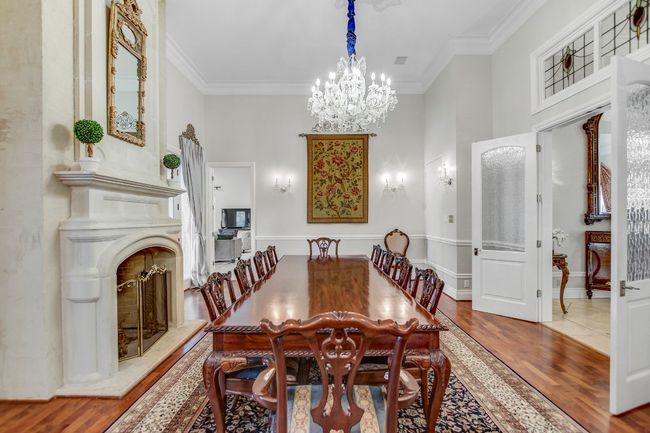Dining area featuring wood finished floors, crown molding, a chandelier, and a fireplace with raised hearth | Image 15