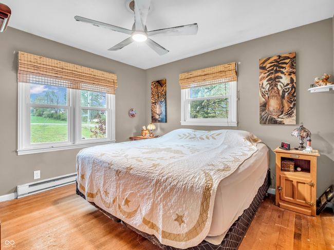 bedroom featuring a baseboard heating unit, ceiling fan, baseboards, and wood-type flooring | Image 27