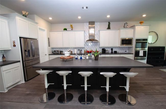 This stunning kitchen features ample white cabinets, stainless steel appliances and a large island creating a perfect space for cooking and entertaining. | Image 7