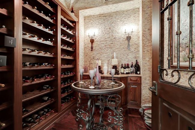 Wine Cellar has walnut floor, groin vault ceiling, limestone walls, marble bar, wine refrigerator, Mexican antique door and custom wine racks. | Image 6