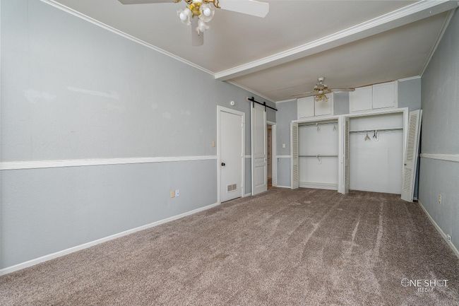 Unfurnished living room featuring a barn door, crown molding, ceiling fan, and carpet floors | Image 19