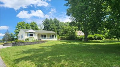 Ranch-style house with covered porch and a front yard | Image 1