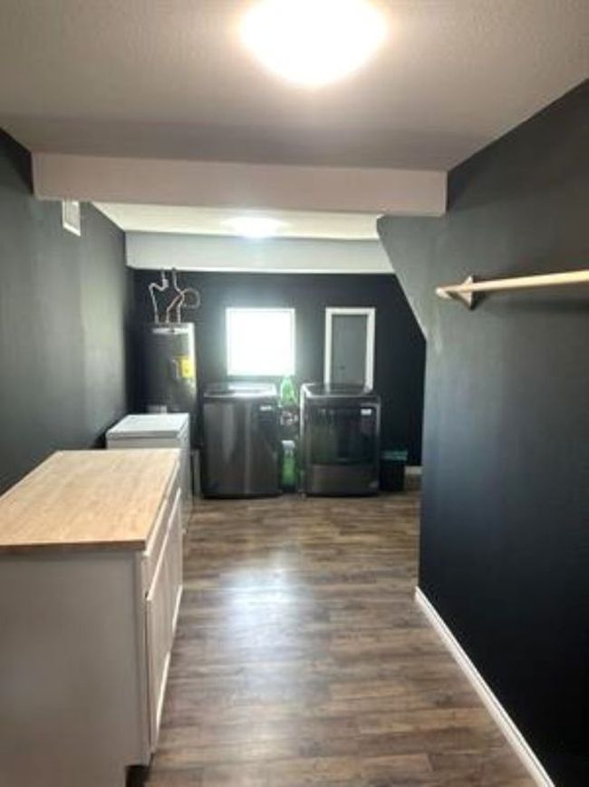 Laundry area with dark wood-style flooring, washer / clothes dryer, and water heater | Image 17