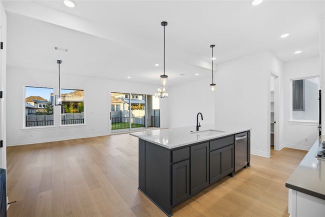 Kitchen with a chandelier, light wood-type flooring, recessed lighting, a kitchen island with sink, and hanging light fixtures | Image 24