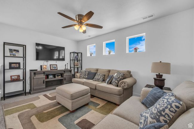 Carpeted living room with ceiling fan and visible vents | Image 11