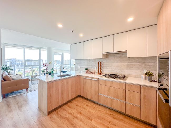Kitchen with stainless steel gas stovetop, a peninsula, a view of city, light wood finished floors, and recessed lighting | Image 6