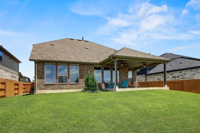 Rear view of property featuring ceiling fan, a fenced backyard, roof with shingles, and brick siding | Image 34
