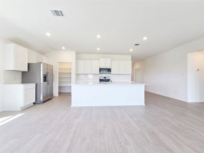 Kitchen with stainless steel appliances, decorative backsplash, light countertops, a center island with sink, and recessed lighting | Image 18