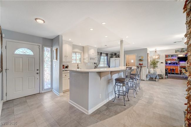Kitchen featuring white appliances, white cabinets, light countertops, a kitchen breakfast bar, and a spacious island | Image 53