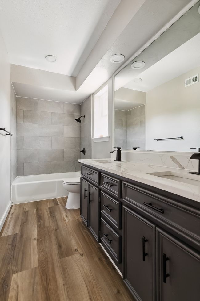 Bathroom featuring wood finished floors, toilet, vanity, visible vents, and washtub / shower combination | Image 32