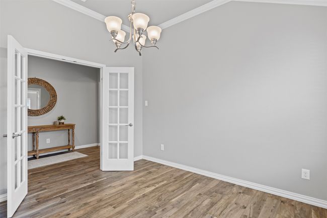 Formal dining room or office with french doors, a chandelier, wood finished floors, and ornamental molding | Image 11