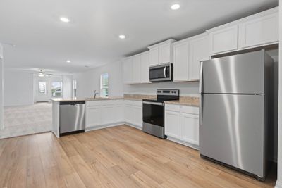 Chef ready kitchen which includes a suite of energy-efficient Whirlpool appliances - including refrigerator with ice maker, granite countertops, designer white cabinetry and luxury vinyl plank flooring | Image 3