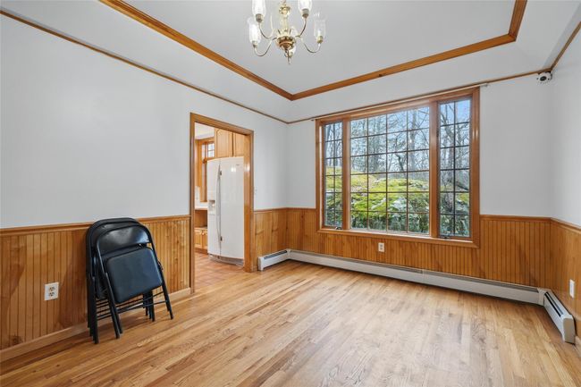 Unfurnished room with light wood finished floors, a wainscoted wall, and a chandelier | Image 20