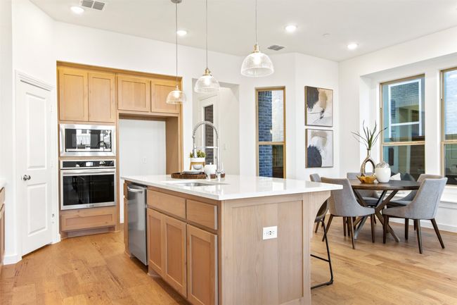 Kitchen featuring appliances with stainless steel finishes, light wood-type flooring, pendant lighting, an island with sink, and recessed lighting | Image 17