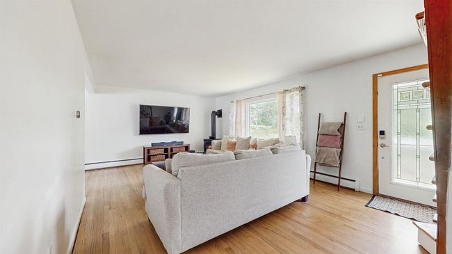 Living room featuring a baseboard heating unit, light wood finished floors, entry and a gas stove. | Image 10