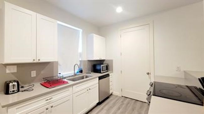 Kitchen with appliances with stainless steel finishes, white cabinets, light wood finished floors, light countertops, and recessed lighting | Image 9