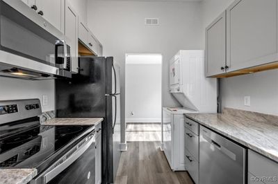 Kitchen featuring appliances with stainless steel finishes, dark hardwood / wood-style floors, and white cabinetry | Image 2