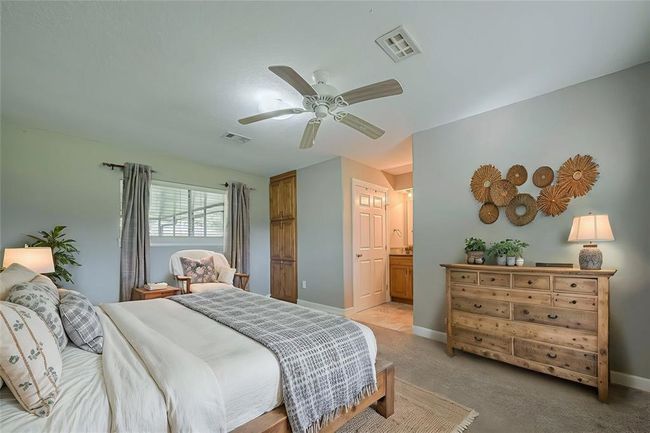 Spacious primary bedroom offers plenty of natural lighting from windows on two walls, a built-in wall storage cabinet, and an en-suite bathroom.(AI photo) | Image 13