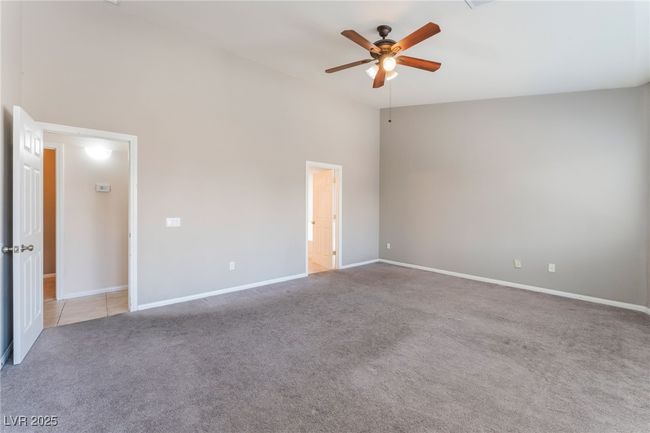 Unfurnished bedroom featuring light carpet, baseboards, a ceiling fan, and a high ceiling | Image 27