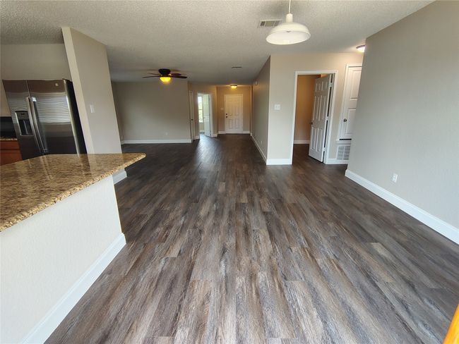 Unfurnished living room with ceiling fan, dark wood-type flooring, a textured ceiling, and baseboards | Image 7