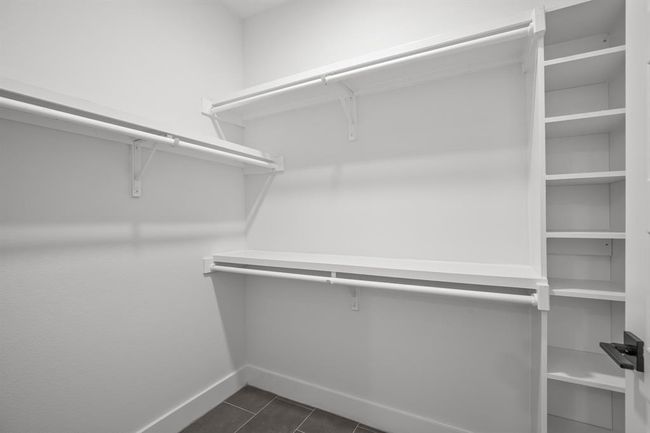 Spacious walk-in closet featuring dark tile patterned floors | Image 16