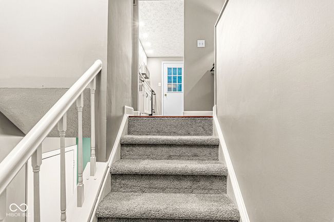 stairway featuring a textured ceiling and carpet | Image 33