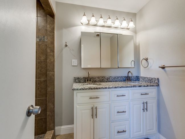 Full bath with double vanity, tiled shower, and baseboards | Image 19