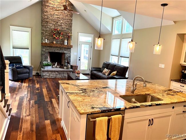 Kitchen featuring open floor plan, reclaimed oak wood finished floors, white cabinets, light stone countertops, and high vaulted ceiling | Image 6