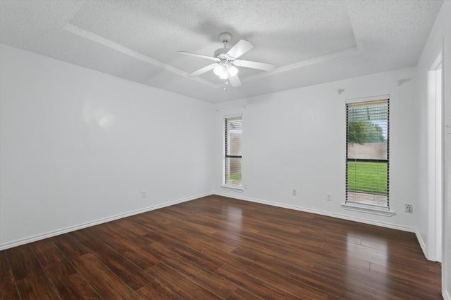 Spare room with healthy amount of natural light, a raised ceiling, a textured ceiling, and dark wood-style floors | Image 16