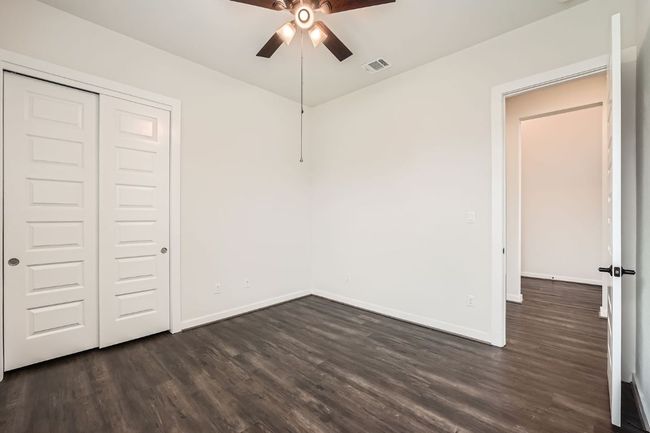 Unfurnished bedroom with dark wood-style flooring, baseboards, a closet, and ceiling fan | Image 20